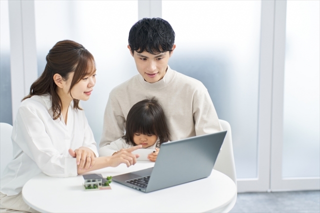 パソコンを見ながら家を検討する夫婦
